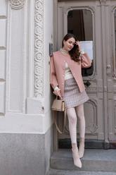 a lady in a knitted top, a pink jacket and a skirt